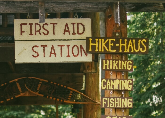 Signs for the First Aid Station and Hike-Haus in a forest setting.